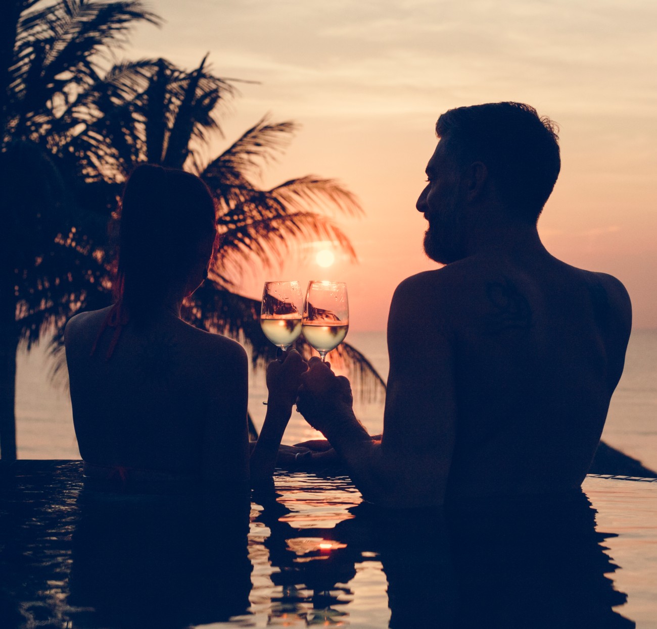 Καλοκαιρινός έρωτας, ζευγάρι πίνει κρασί μέσα σε πισίνα