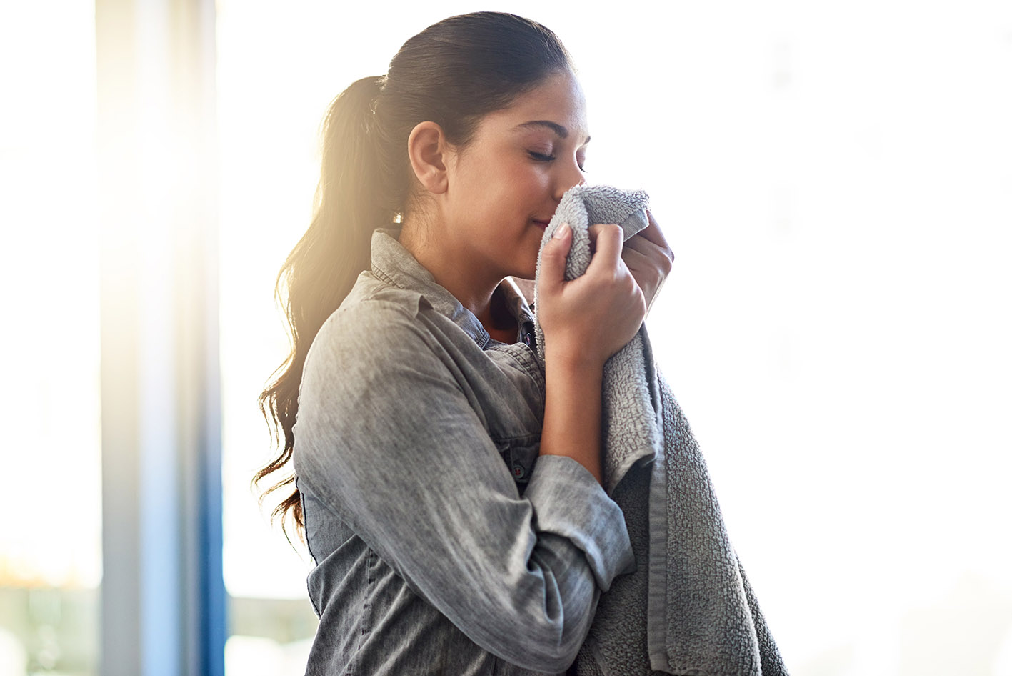 Γυναίκα χαμογελά μυρίζοντας καθαρά ρούχα