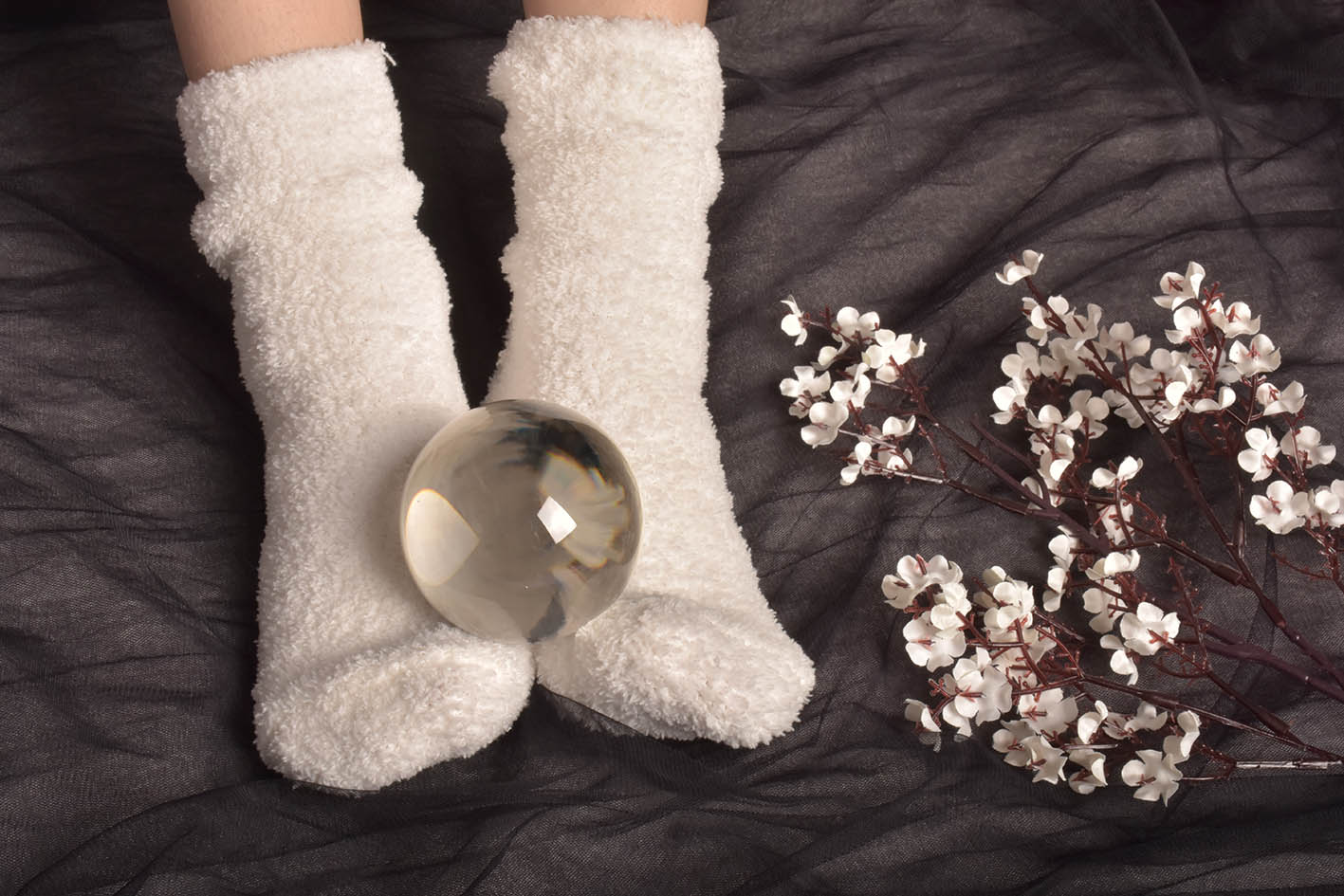 Πατούσες γυναίκας με άσπρες κάλτσες και μια γυάλινη μπάλα πάνω τους