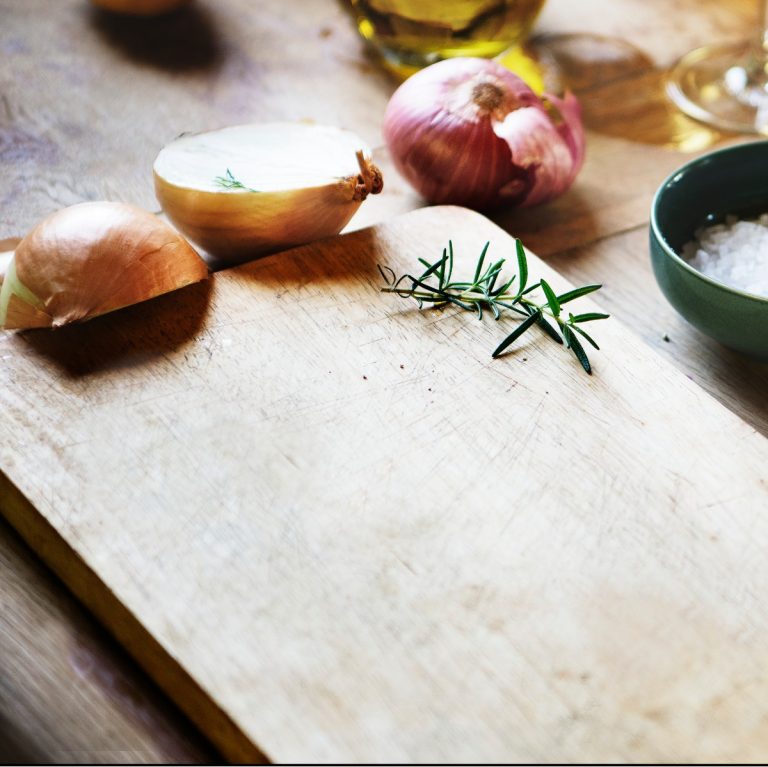 Κρεμμύδια σε ξύλο κοπής στην κουζίνα
