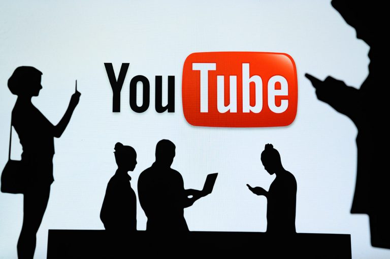 Πλατφόρμα διαδικτυακής κοινής χρήσης βίντεο YouTube. Ομάδα επιχειρηματιών συνομιλούν σε κινητό τηλέφωνο και φορητό υπολογιστή. Το λογότυπο της εταιρείας εμφανίζεται στην οθόνη στο φόντο.