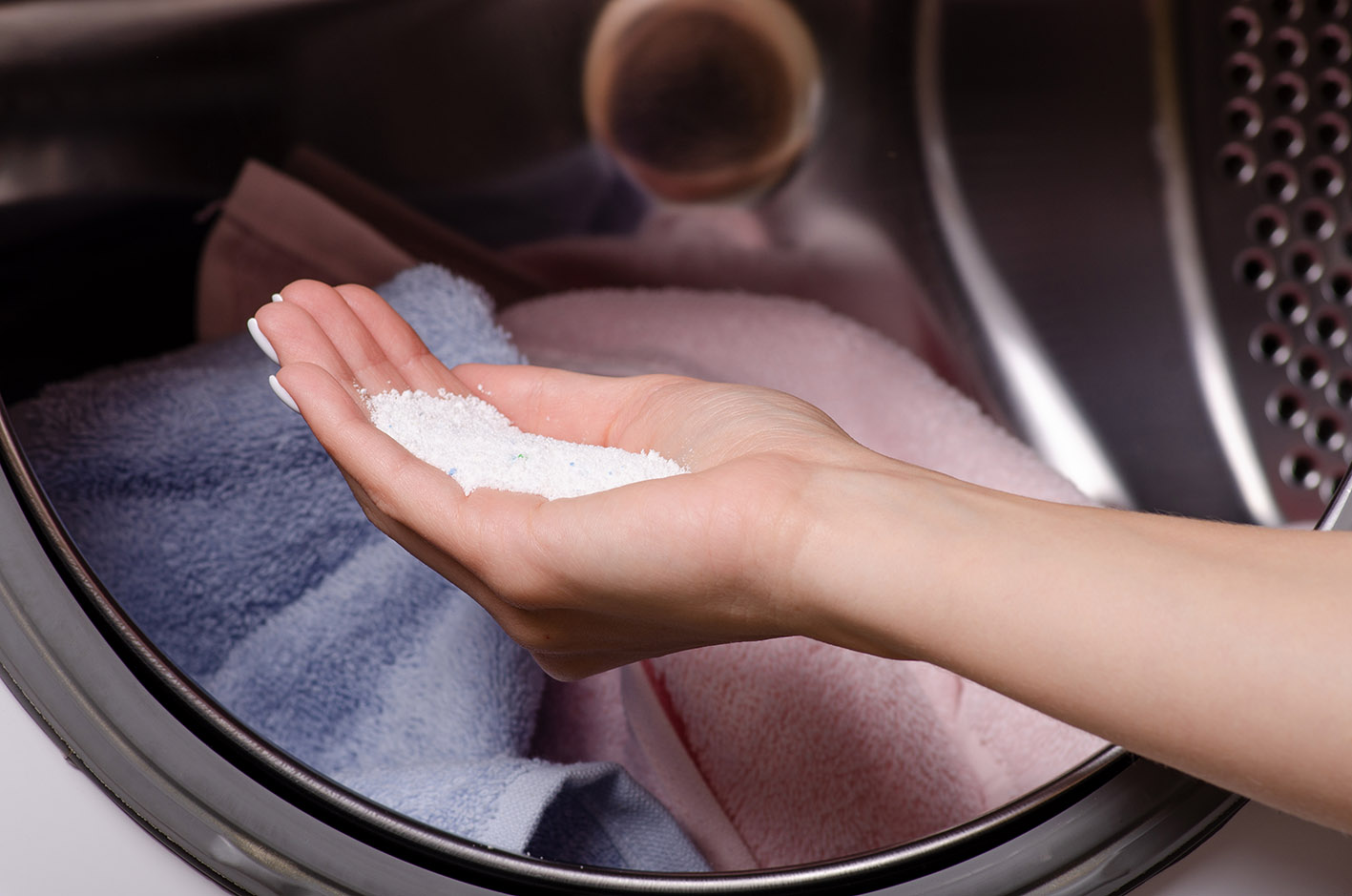 Γυναικεία χούφτα με σκόνη πλυντηρίου έτοιμη για να τη βάλει στον κάδο.