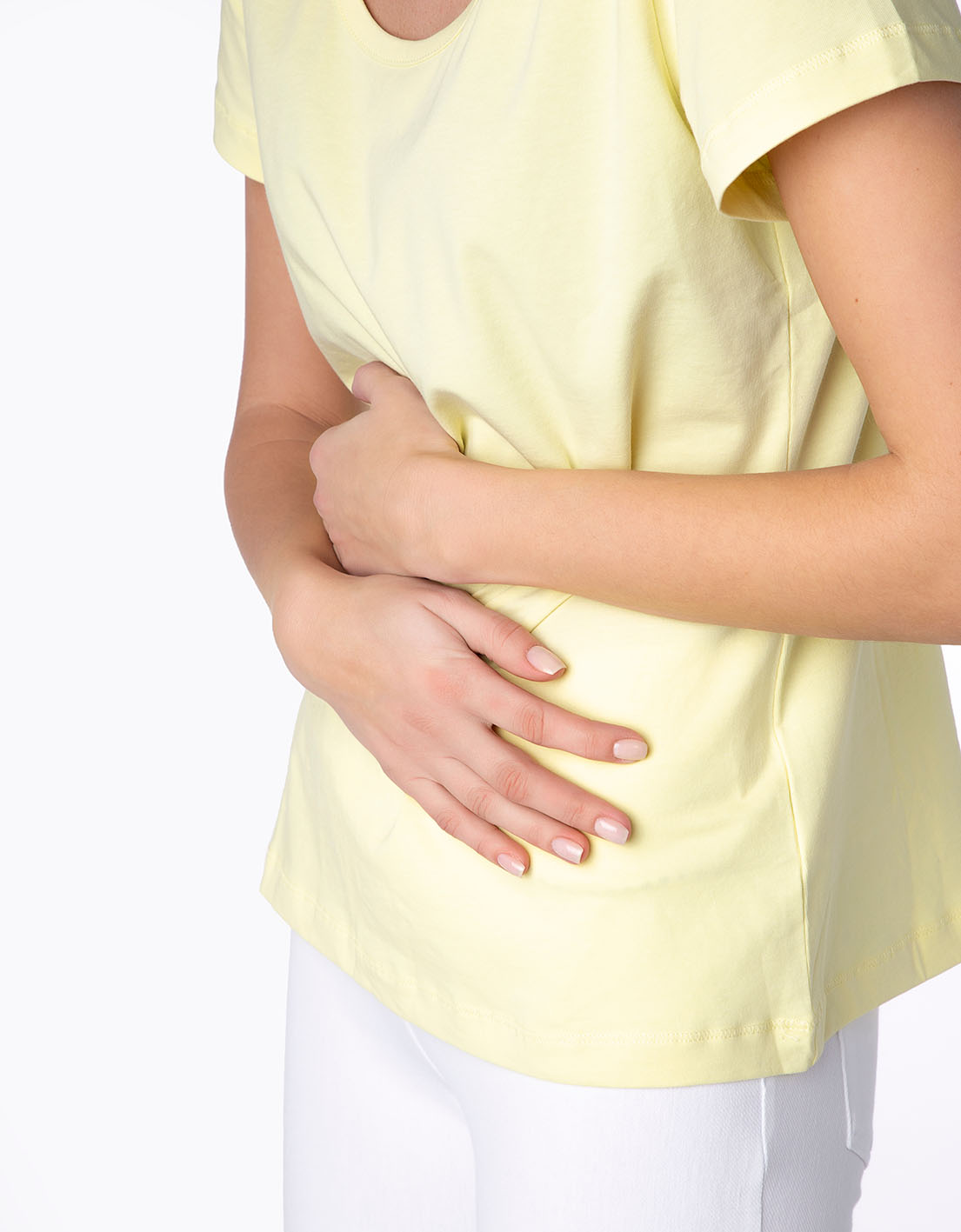 Γυναίκα κρατά την κοιλιά της γιατί πονά