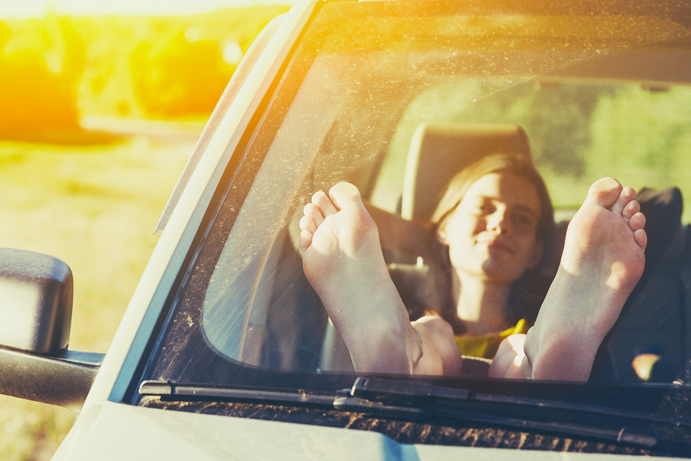 Γυναίκα συνοδηγός με τα πόδια της πάνω στο καντράν αυτοκινήτου.