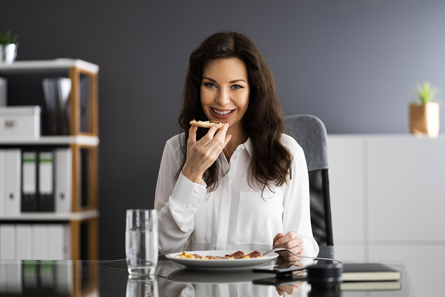 Γυναίκα στο γραφείο κάνει διάλειμμα και τρώει