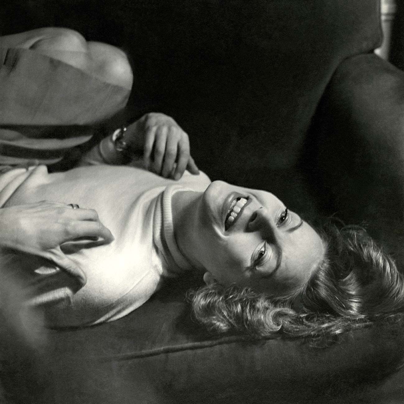 H ηθοποιός Greta Garbo (1905 - 1990) φορώντας ένα άσπρο πουλόβερ με ζιβάγκο και ξαπλωμένη ανάσκελα χαμογελώντας. Φωτογραφία του Cecil Beaton για τη Vogue 1945.