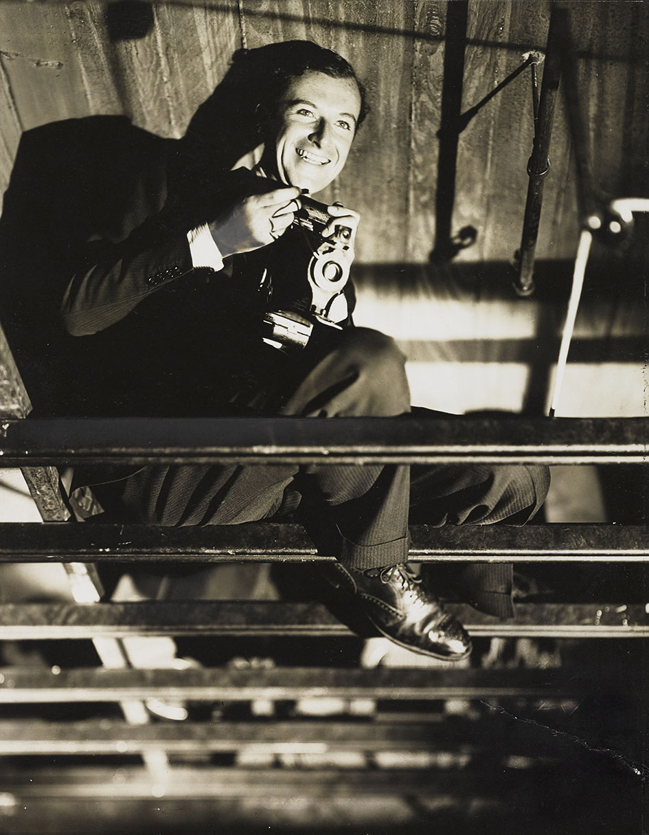 Αυτοπροσωπογραφία του φωτογράφου Cecil Beaton με τη φωτογραφική μηχανή στο χέρι σε σκαλωσιά στο στούντιο.