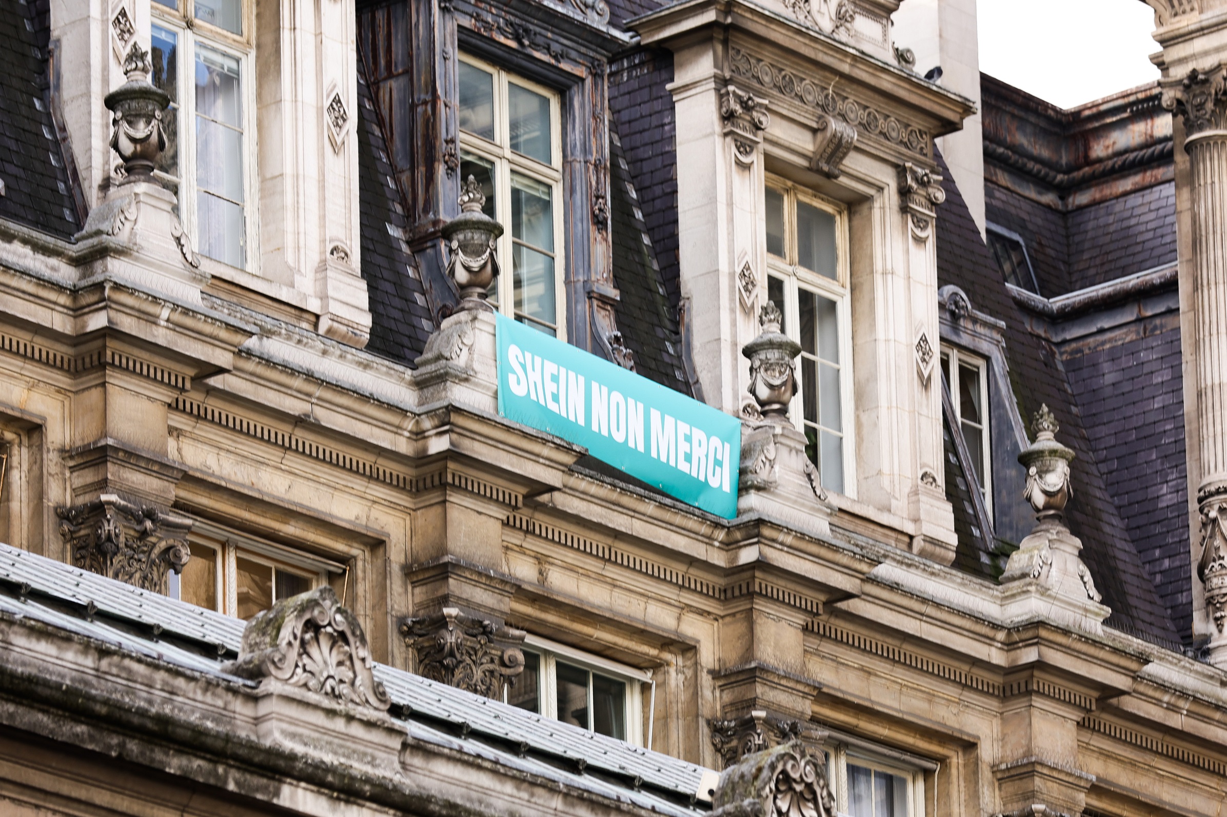 Πανό "Shein όχι ευχαριστώ" κρέμεται έξω από το Δημαρχείο του Παρισιού την ημέρα λειτουργίας του καταστήματος της Shein, 5 Νοεμβρίου 2025 