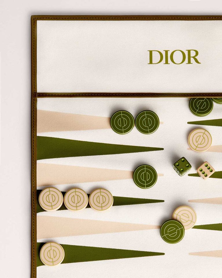 Σετ τάβλι ταξιδιού της Dior, ειδικά η έκδοση "Green CD Entrelacés Cotton and Cowhide Leather". Είναι κατασκευασμένο από 52% βαμβάκι και 9% δέρμα βοοειδών, με πούλια από PMMA και μεταλλικά στοιχεία από ορείχαλκο με χρυσό φινίρισμα. Όταν είναι τυλιγμένο, έχει διαστάσεις περίπου 10 x 30 cm, καθιστώντας το φορητό. Κατασκευάζεται στη Γαλλία.