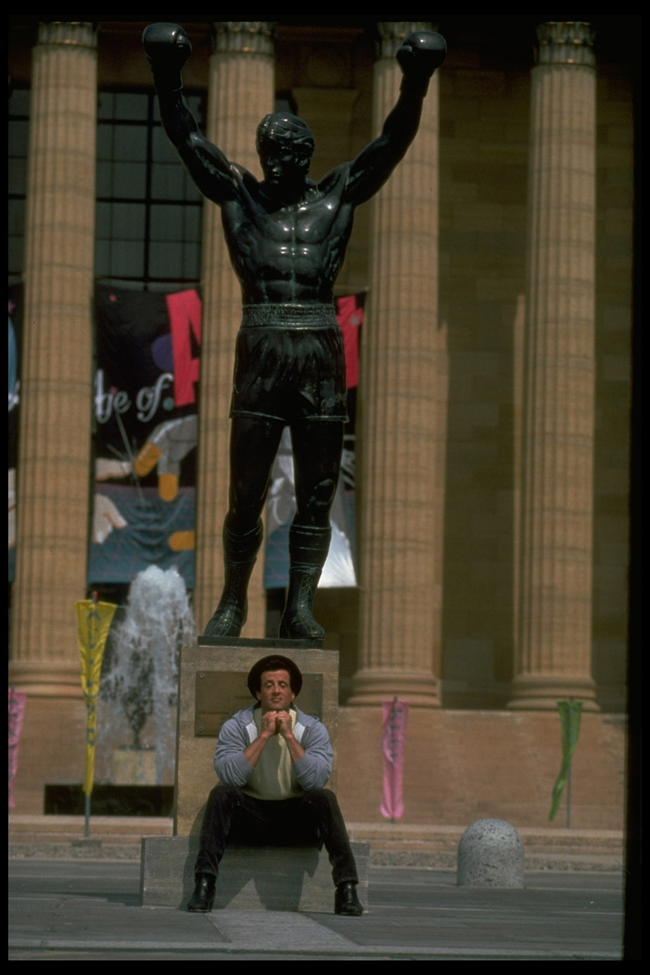 Ο ηθοποιός Sylvester Stallone κάθεται κάτω από το άγαλμα του Ρόκι Μπαλμπόα, χαρακτήρα που έκανε διάσημο στις ταινίες Ρόκι.