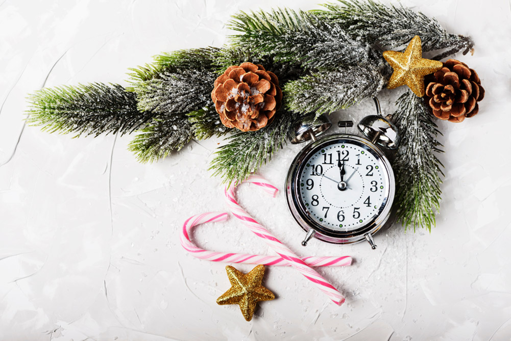 Νέα χρονιά με ρολόγι να δείχνει μεσάνυχτα και κλαρί δέντρου χριστουγεννιάτικο