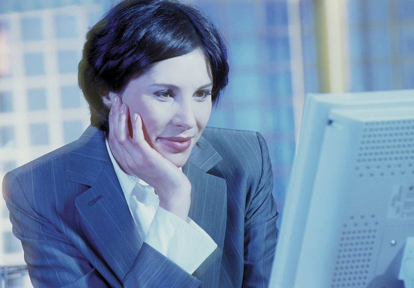 Γυναίκα χαμογελά μπροστά στην οθόνη του κομπιούτερ της