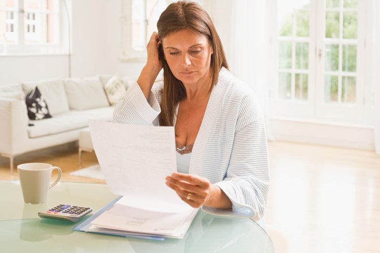 Γυναίκα ελέγχει οικονομικά έγγραφα στο σπίτι της