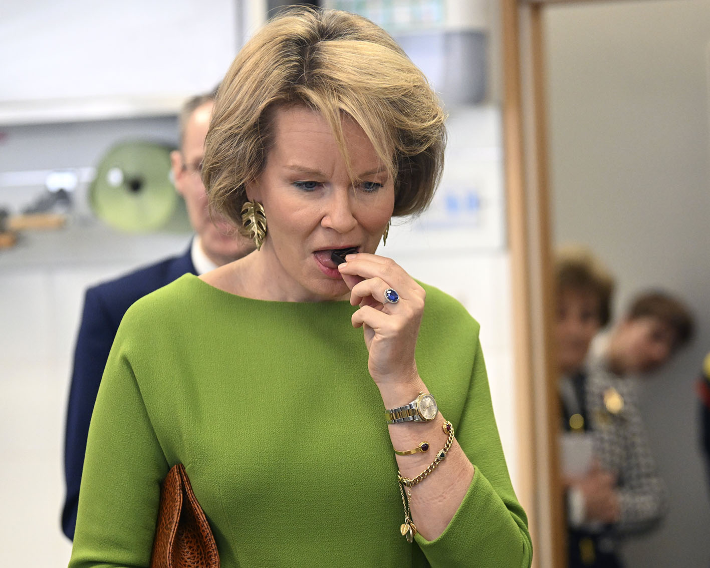 H Bασίλισσα Mathilde τρώγοντας ένα κομμάτι σοκολάτα στις 29 Μαρτίου 2024 σε επίσκεψή της στη Σχολή Ξενοδοχείων της Γάνδης.