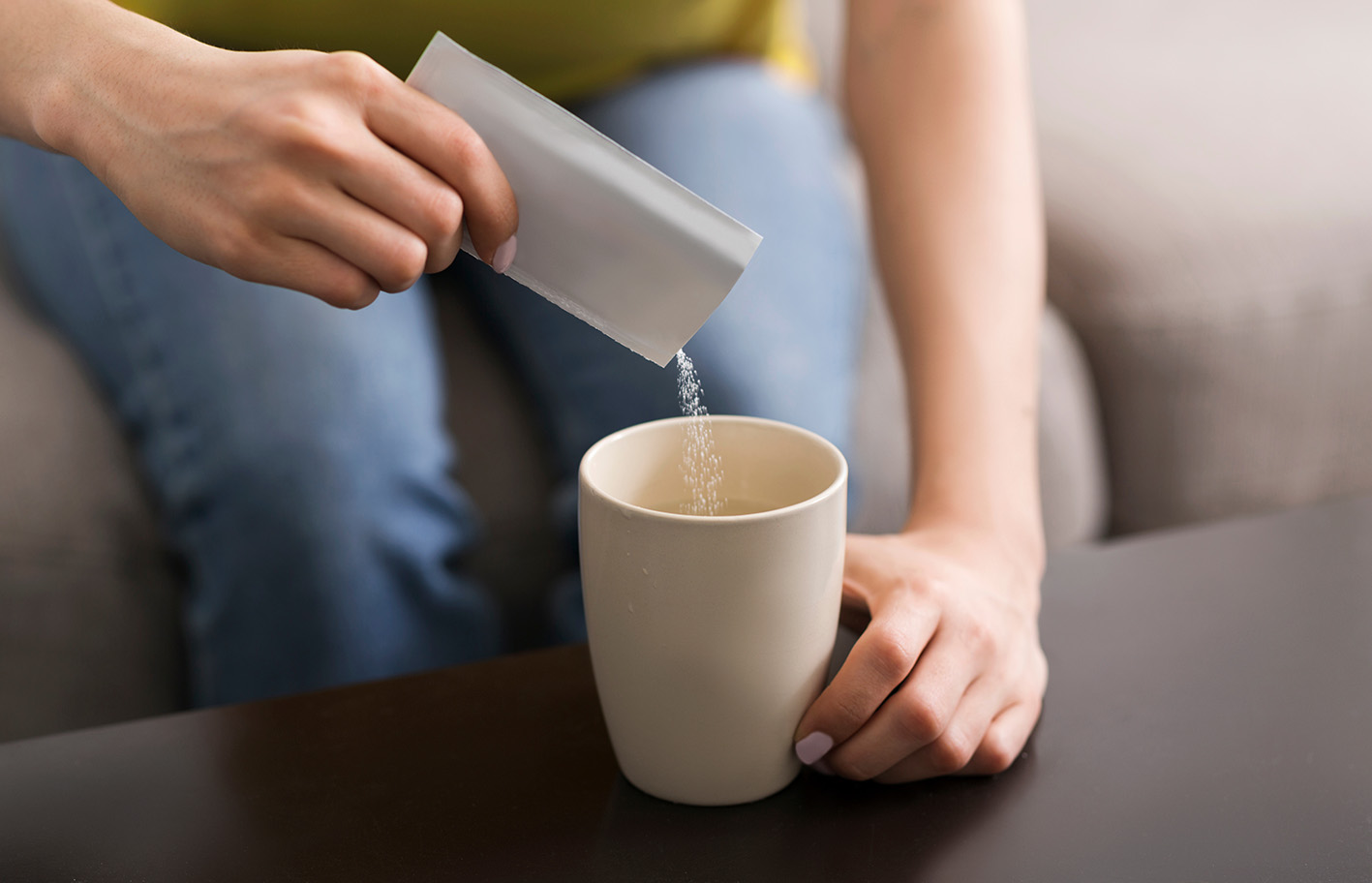 Γυναίκα βάζει στον καφέ ή τσάι της ζαχαρίνη