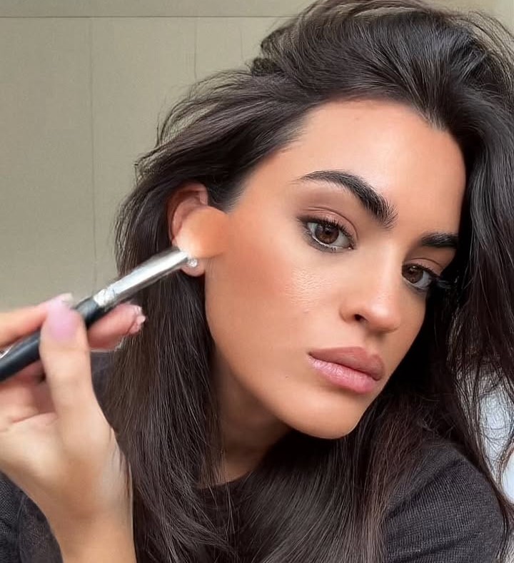 Γυναίκα απλώνει προϊόντα μακιγιάζ