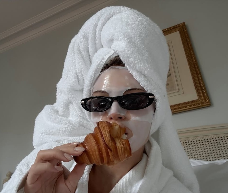 Γυναίκα με μάσκα ομορφιάς τρώει κρουασάν