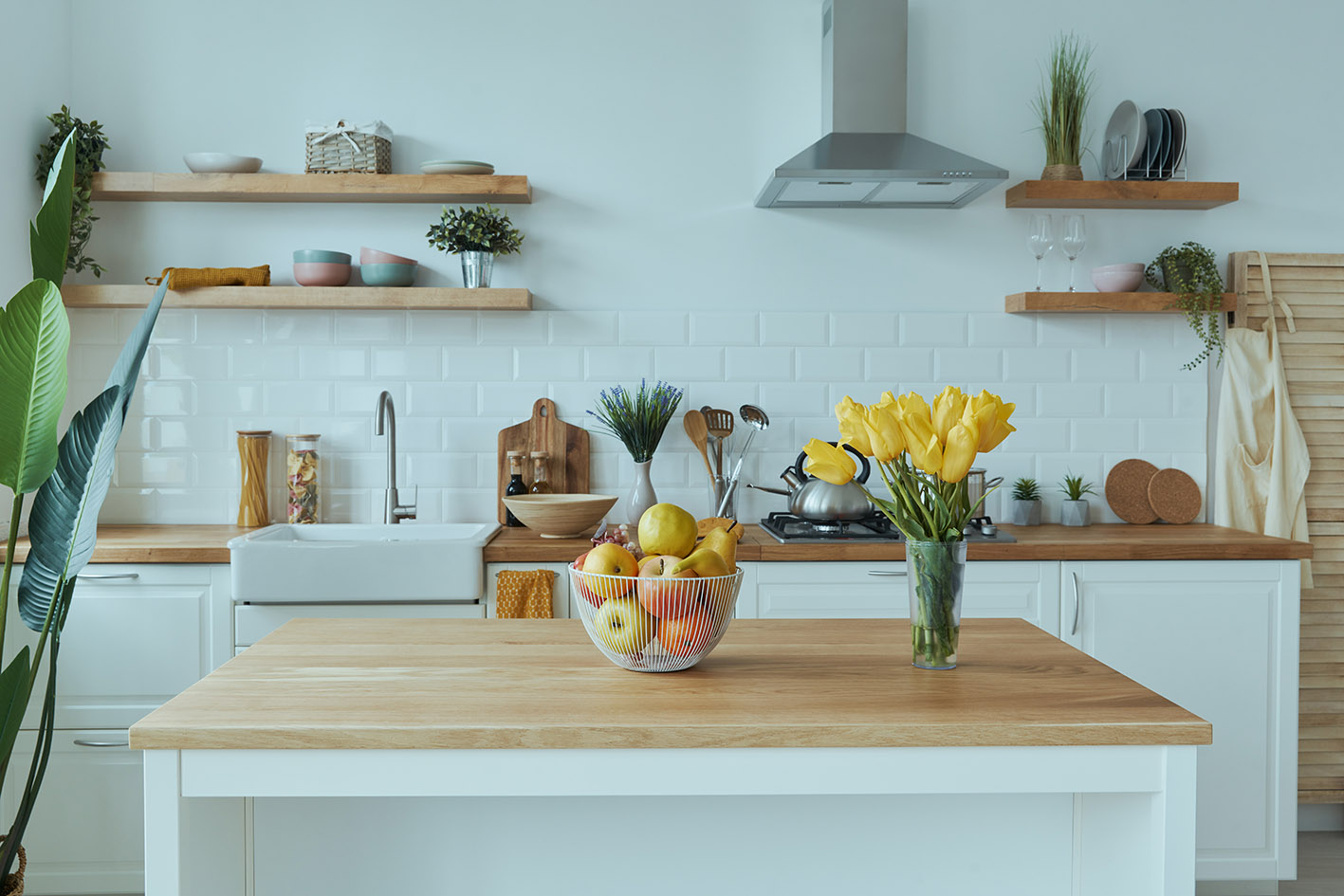 Μοντέρνα λευκή κουζίνα με ξύλινο πάγκο και λουλούδια