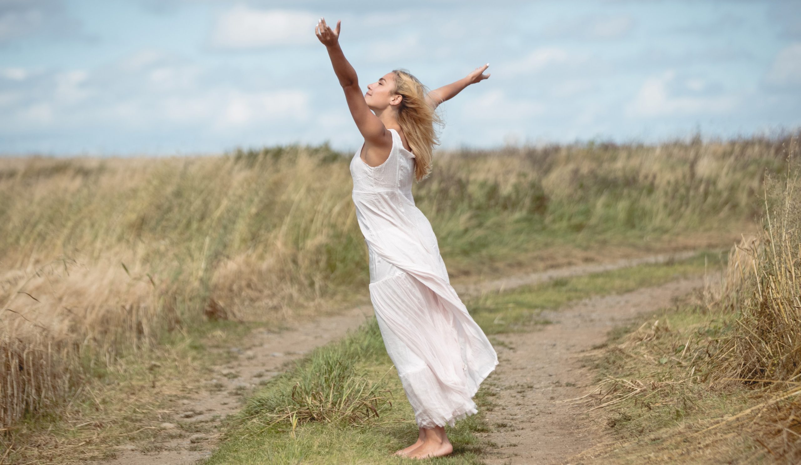 Γυναίκα χαρούμενη στη φύση με ανοιχτά τα χέρια της. Απελευθερωμένη από το παρελθόν λόγω 24ης Μαρτίου.