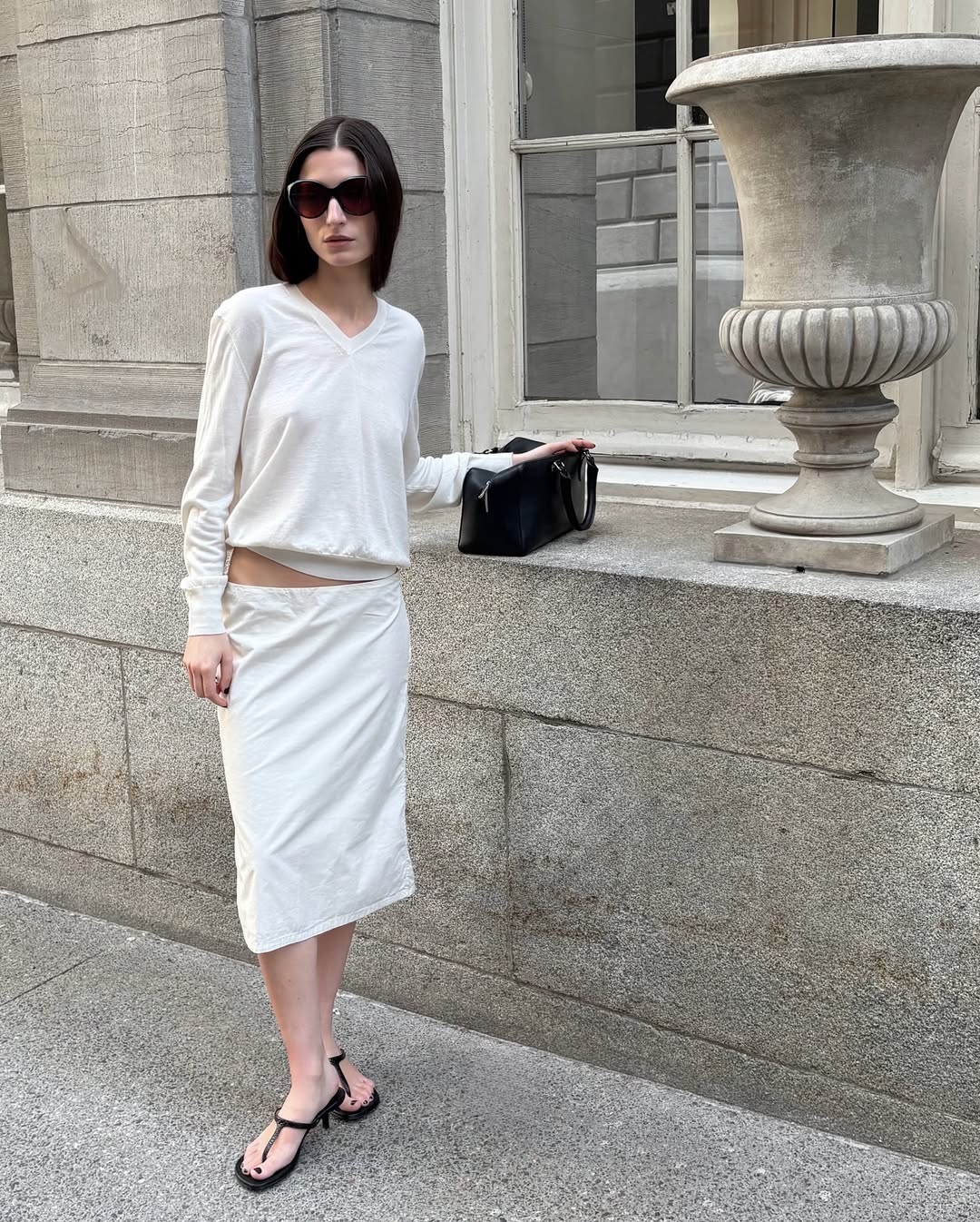 Andrea Ricci με λευκό σύνολο και μεγάλα μαύρα γυαλιά ακολουθώντας το στιλ της Carolyn Bessette.