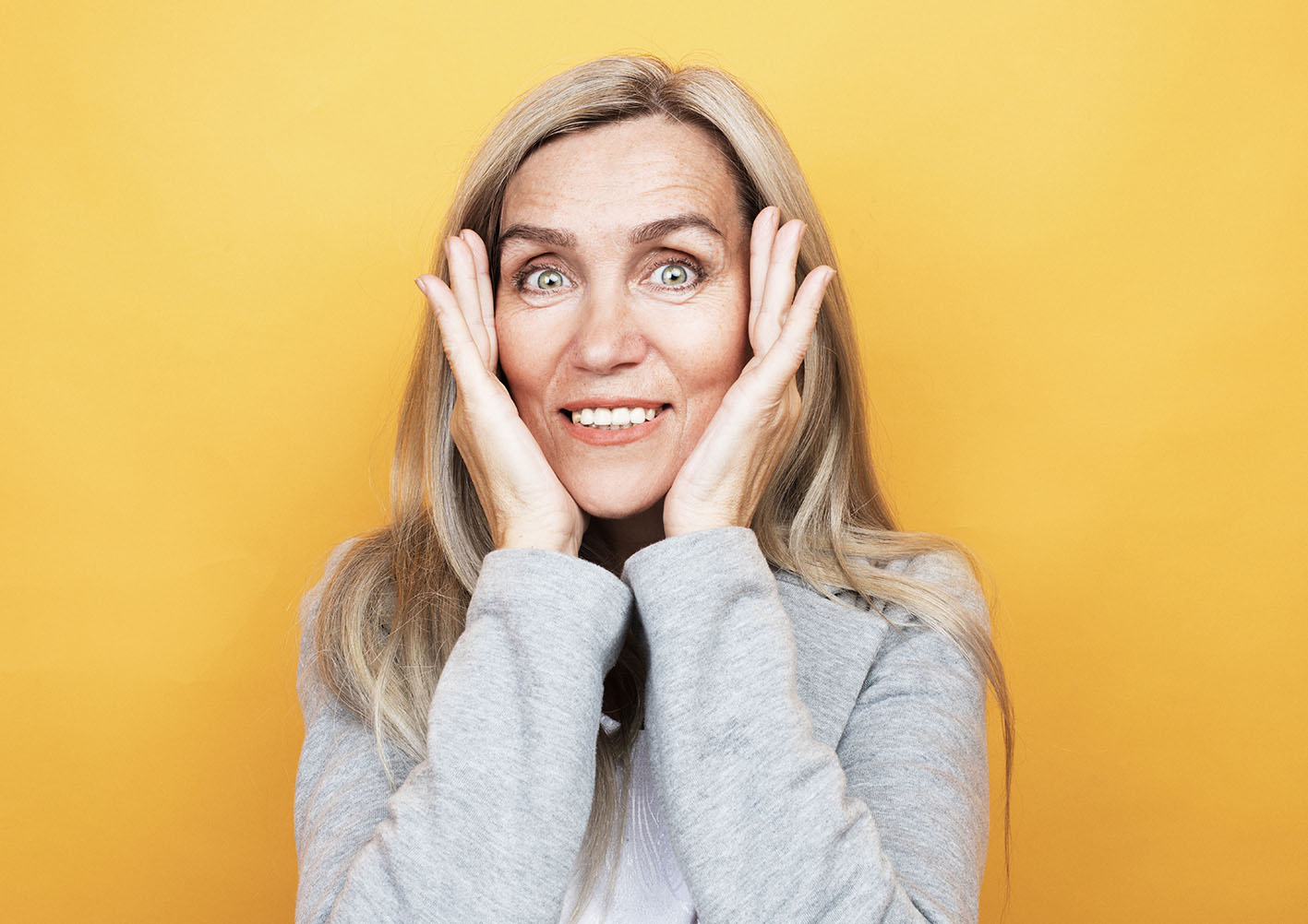 Γυναίκα είναι λίγο σοκαρισμένη και έχει τις παλάμες της να ακουμπούν το κεφάλι της. Χαμογελά ελαφρά