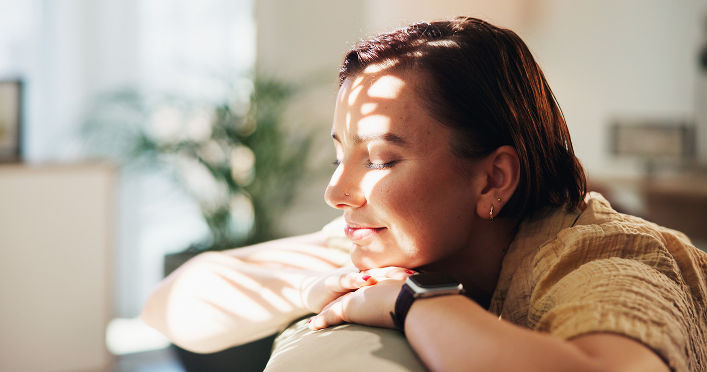 Γυναίκα στο καναπέ ήρεμη με φως του ήλιου στο πρόσωπό της.