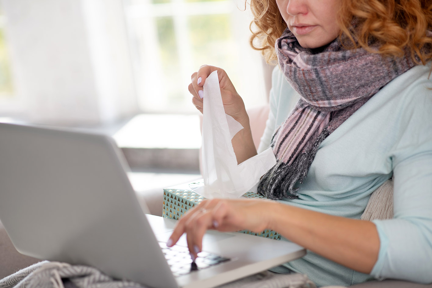 Γυναίκα κρυωμένη δουλεύει στο κομπιούτερ της.