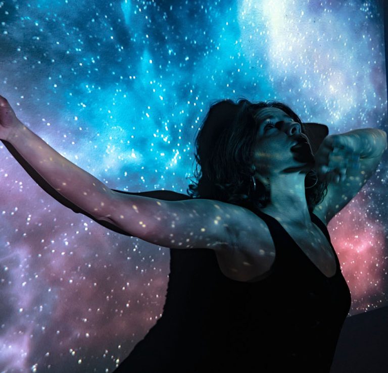 Γυναίκα ήρεμη ακουμπά στον σύμπαν με ανοιχτά χέρια