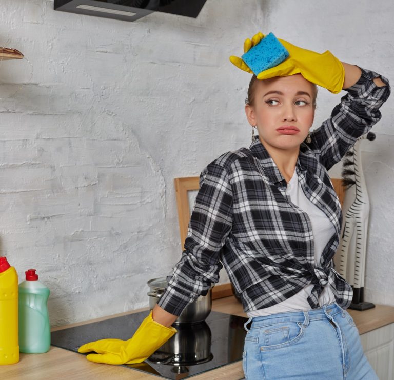 Γυναίκα με γάντια καθαρίζει την κουζίνα κρατώντας ένα σφουγγάρι