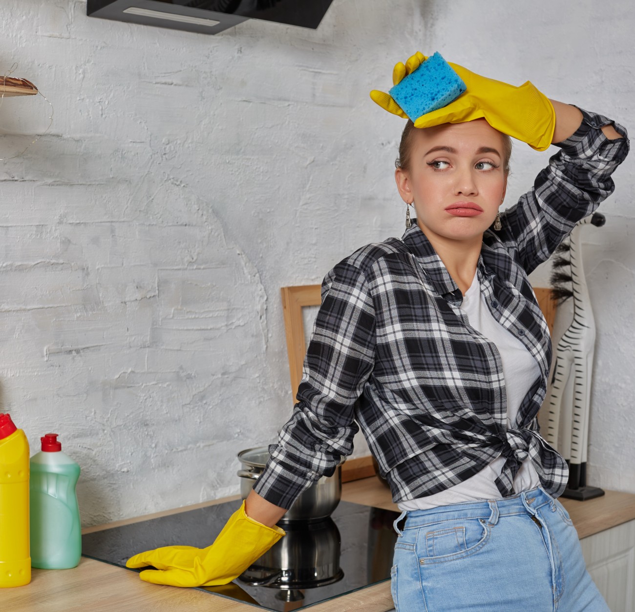 Γυναίκα με γάντια καθαρίζει την κουζίνα κρατώντας ένα σφουγγάρι