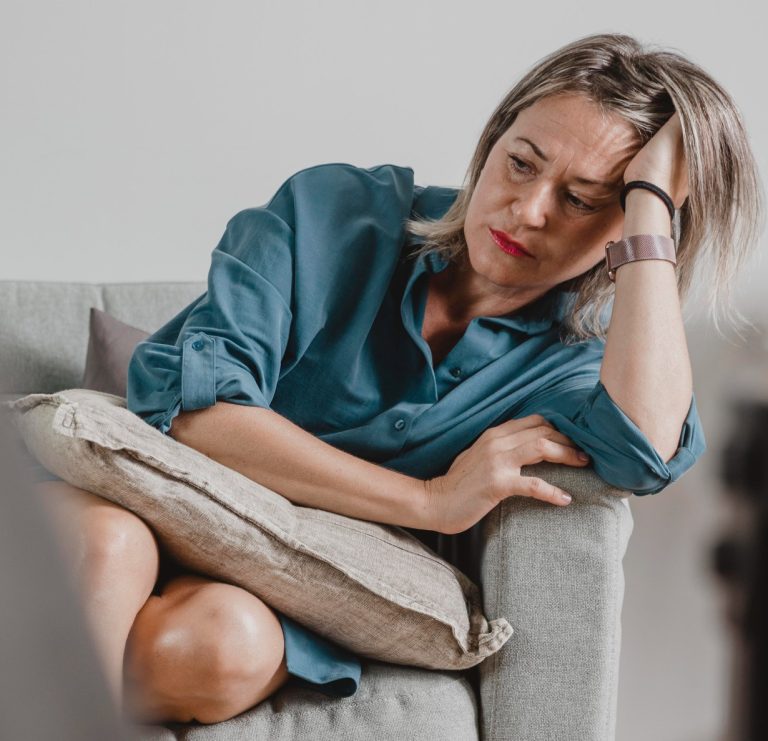 Γυναίκα γύρω στα 45 κάθεται κουρασμένη στον καναπέ