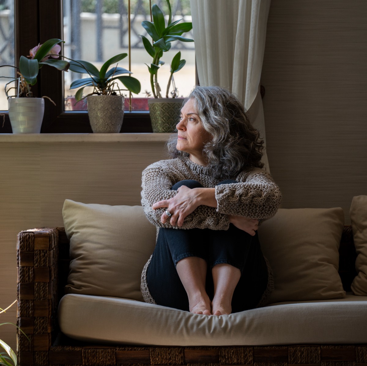 Λυπημένη γυναίκα με γκρίζα μαλλιά καθισμένη σε καναπέ