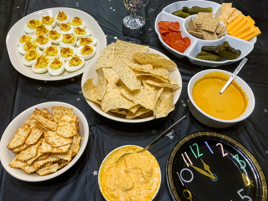 Ένα απολαυστικό μπουφέ με σνακ για το πάρτι, που περιλαμβάνει κρεμώδη γεμιστά αυγά, τραγανά τσιπς τορτίγιας, πικάντικα τουρσιά και μια ποικιλία από αλμυρά κράκερ