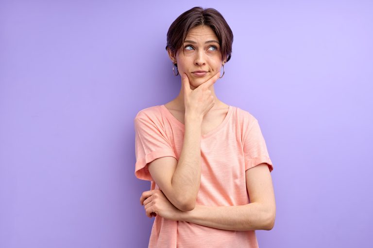 Γυναίκα νέα σκέφτεται κρατώντας με το χέρι της το ένα το πηγούνι.