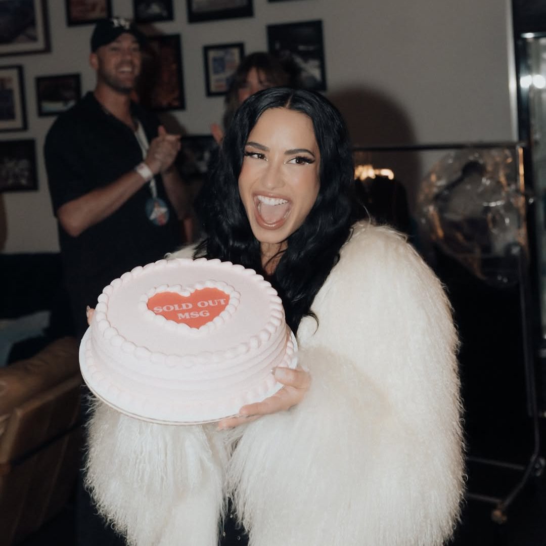 H Demi Lovato με μια τούρτα και μια λευκή γούνα.