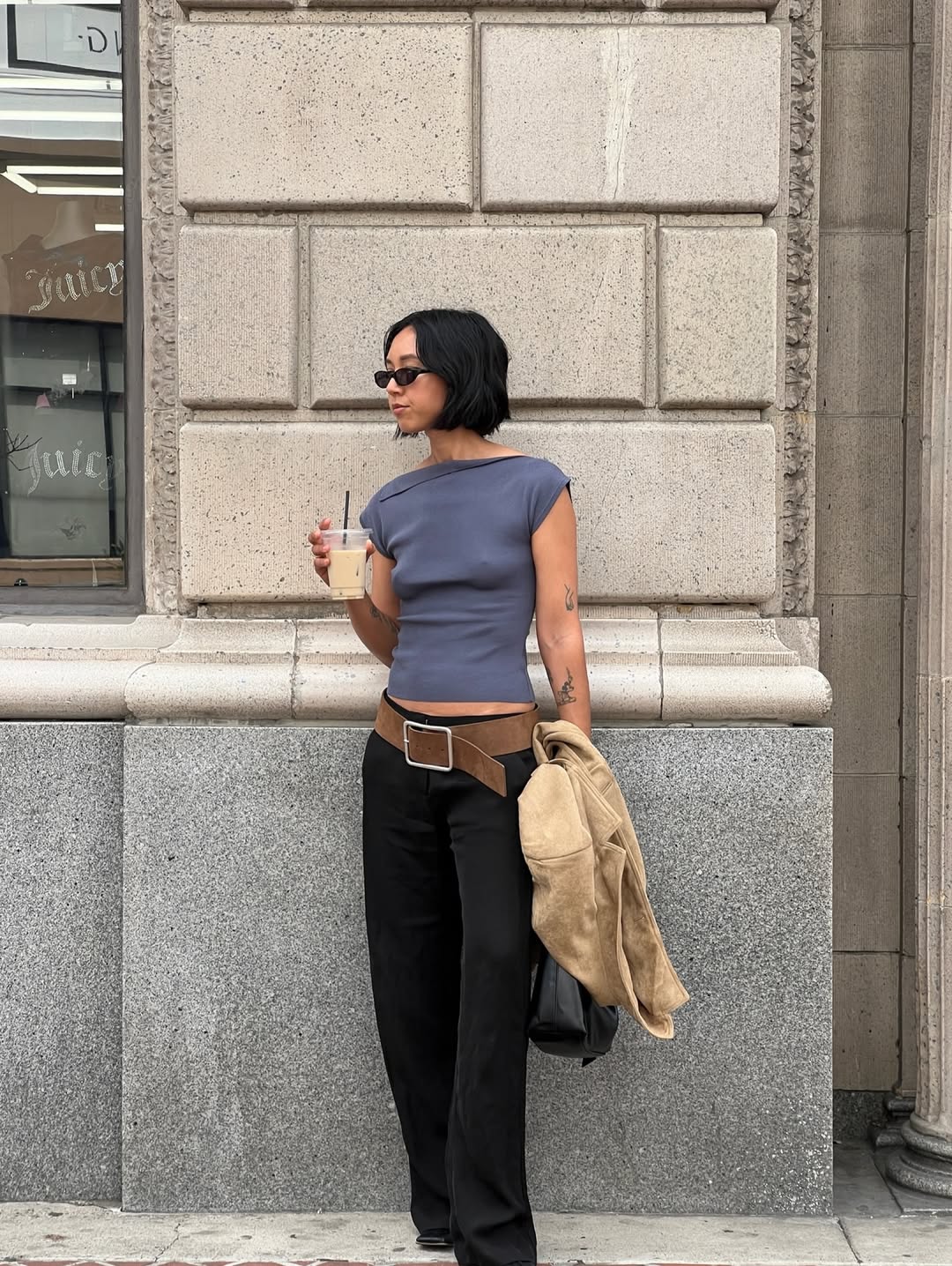 Κοπέλα που φοράει μια καφέ ζώνη με μαύρο παντελόνι και γκρι τοπ.