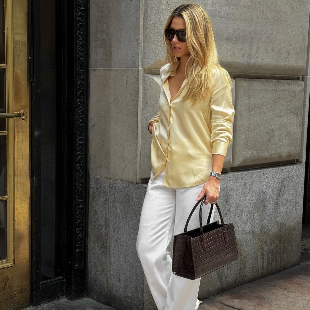 Κοπέλα που φοράει καναρινί πουκάμισο, λευκό τζιν και καφέ τσάντα.
