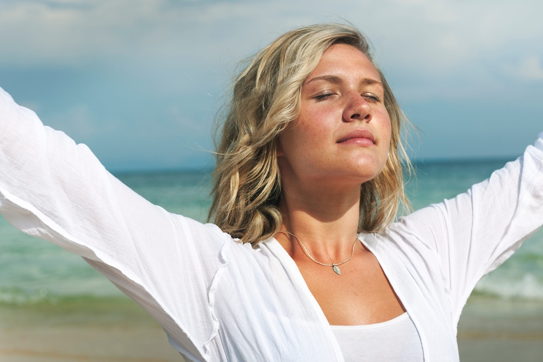 Γυναίκα εισπνέει καθαρό αέρα δίπλα στην ακρογιαλιά για πιο δυνατούς και υγιείς πνεύμονες