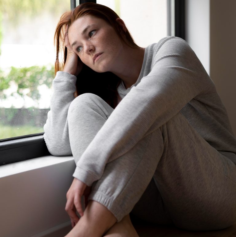 Γυναίκα λυπημένη κοιτάζει έξω από το παράθυρο