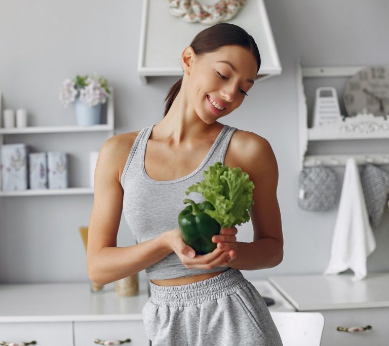 Γυναίκα στην κουζίνα κρατά πράσινα λαχανικά