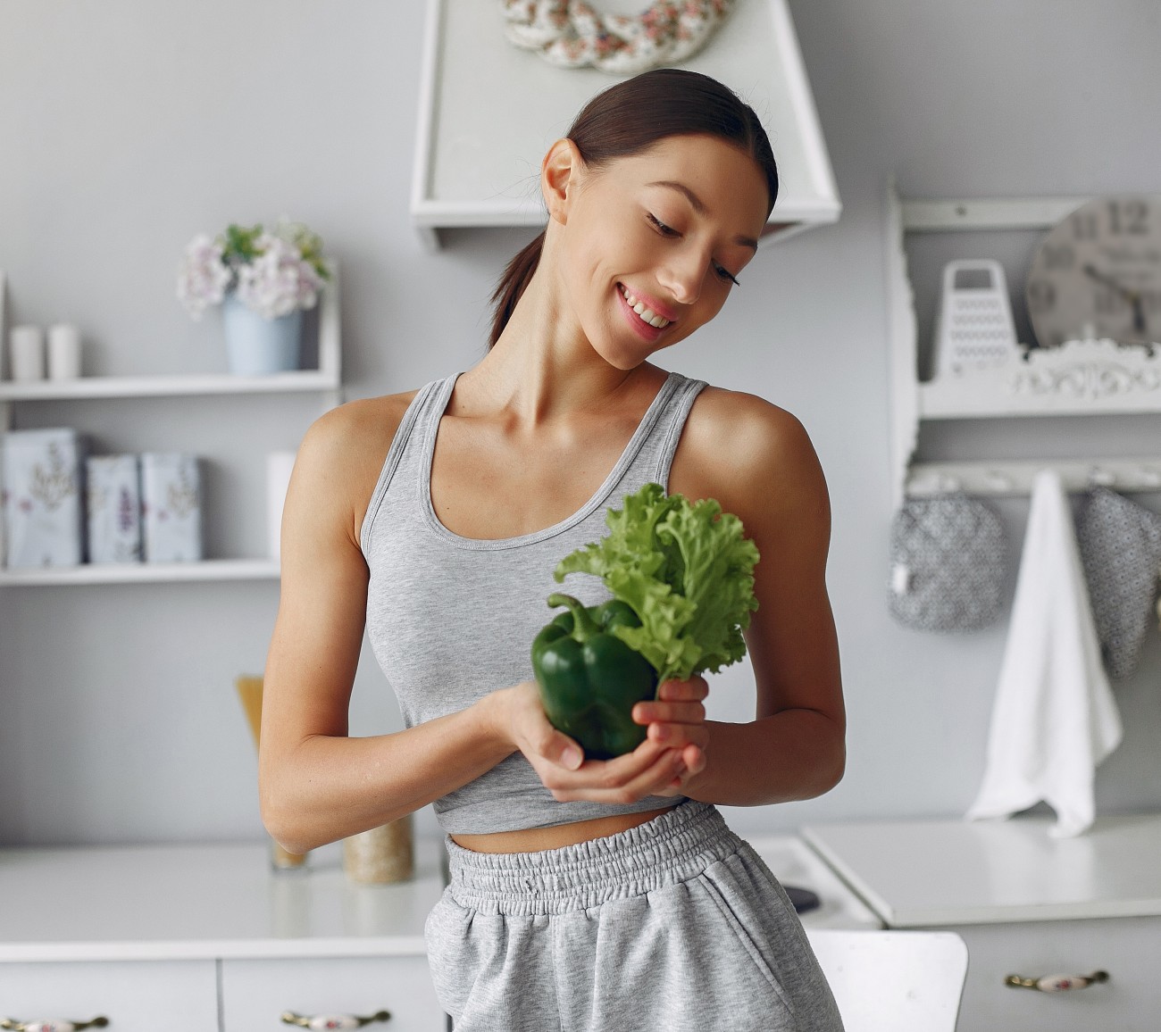 Γυναίκα στην κουζίνα κρατά πράσινα λαχανικά