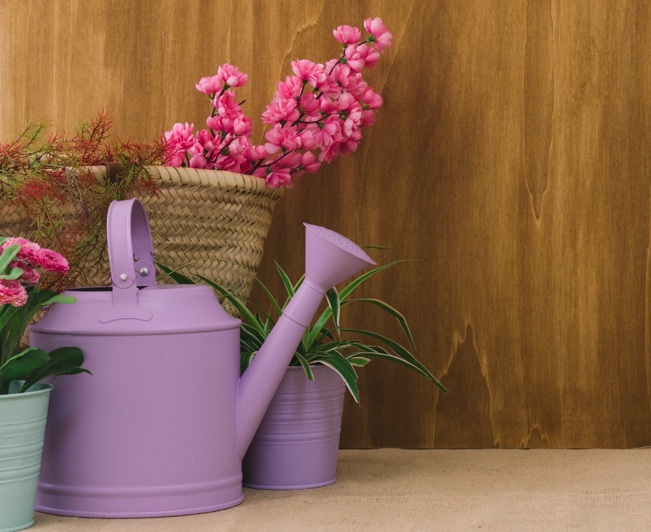 Λουλούδια μέσα σε ψάθινη τσάντα και ποτιστήρι σε μωβ χρώμα