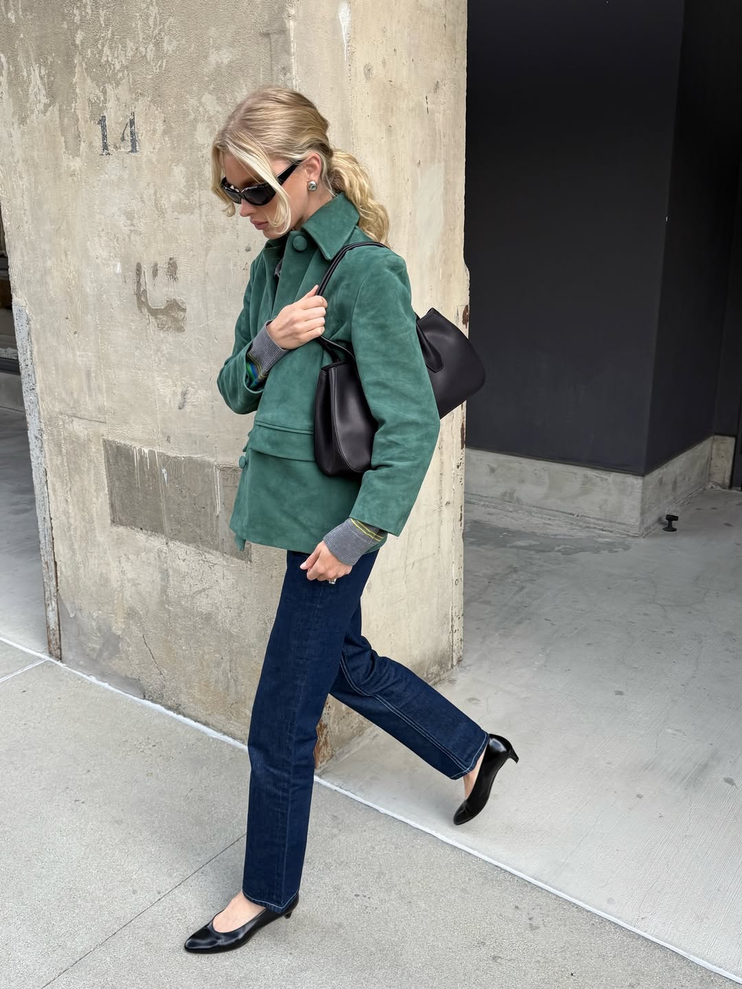 Το μοντέλο Elsa Hosk φοράει ένα κυπαρισσί σουέτ σακάκι, σκούρο μπλε τζιν παντελόνι και μαύρες γόβες με στρογγυλεμένη μύτη και χαμηλό τακούνι.