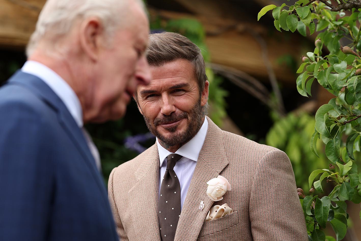 O σερ David Beckham χαμογελάει χαμογελάει καθώς ο βασιλιάς της Βρετανίας Κάρολος Γ΄ επισκέπτεται το RHS Chelsea Flower Show, φορώντας στο πέτο του το δικό του τριαντάφυλλο.