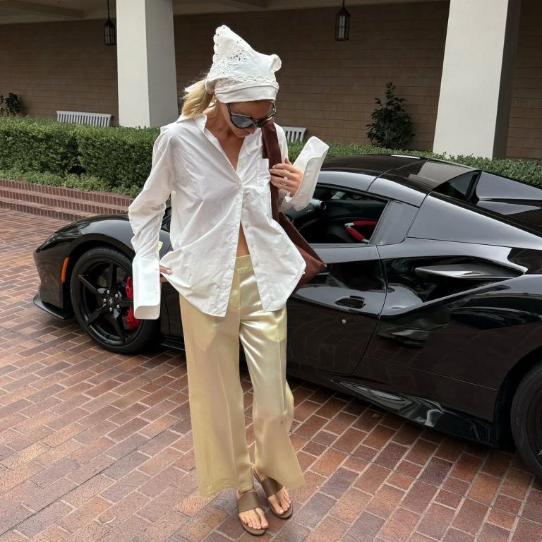 Η Elsa Hosk φοράει λευκό oversized πουκάμισο, μεταξωτό παντελόνι, μπαντάνα στα μαλλιά και stretch thong πέδιλα.