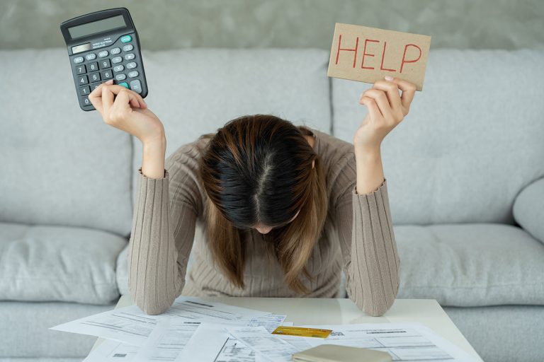 Γυναίκα στο ένα χέρι κρατά χαρτόνι που γράφει βοήθεια και στο άλλο έναν calculator, μια αριθμομηχανή. Δεν της φτάνουν τα χρήματα για τον μήνα.