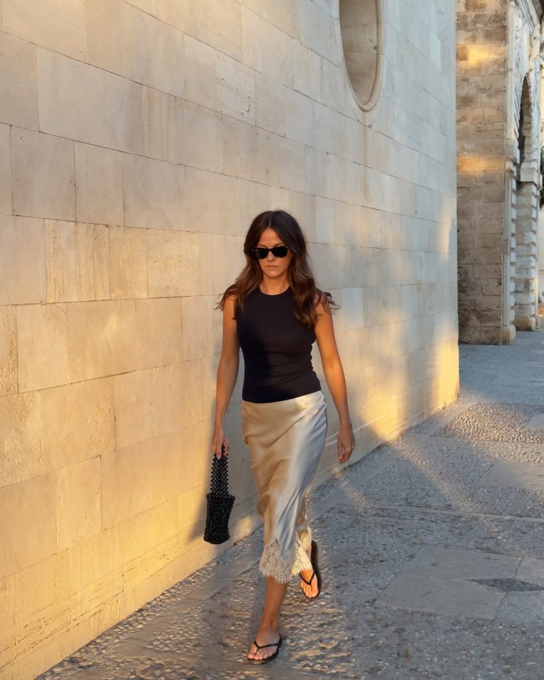 Κοπέλα με μαύρο halter neck τοπ, λευκή δαντελένια φούστα, μαύρες σαγιονάρες και μίνι πλεκτή τσάντα με μαύρες χάντρες.