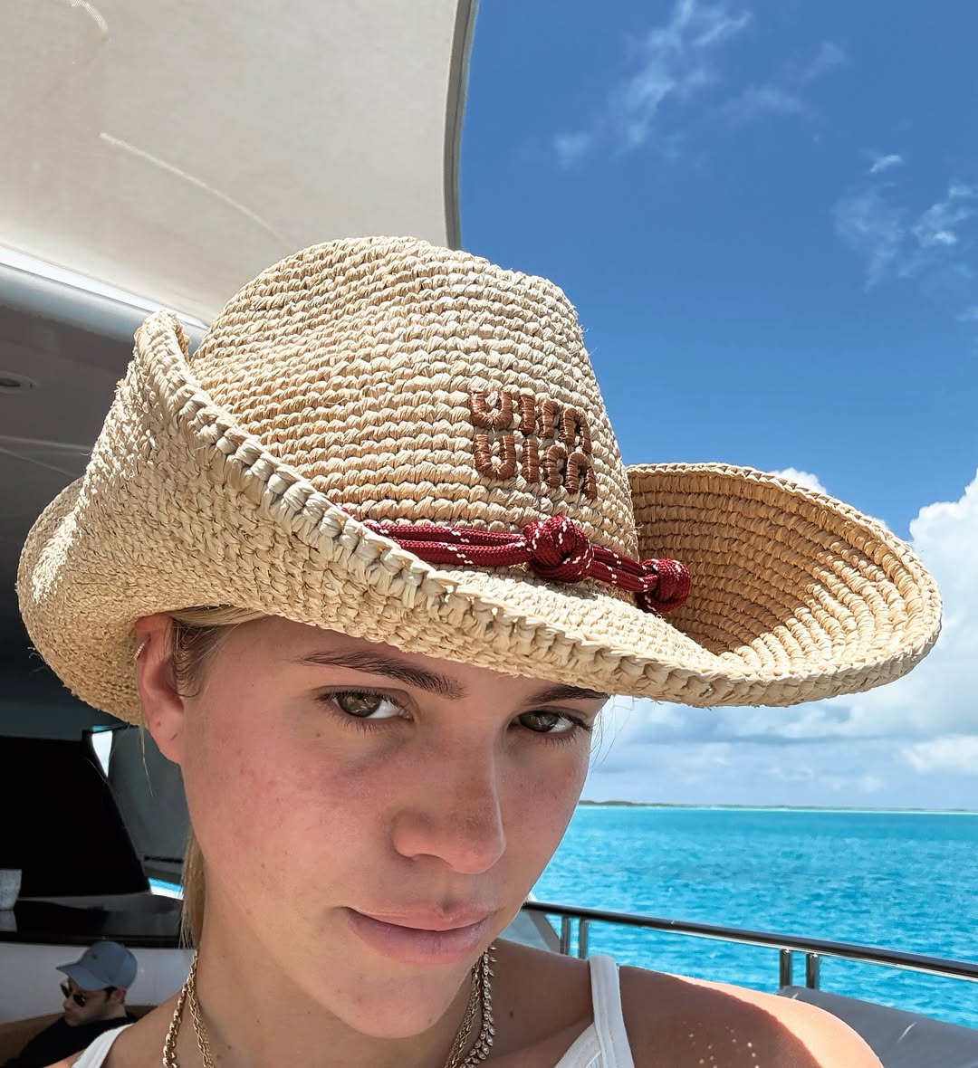Η Sofia Richie Grainge φοράει ανοιχτόχρωμο ψάθινο καπέλο Miu Miu με κόκκινη λεπτομέρεια, λανσάροντας την cowboy core τάση για τα καπέλα παραλίας.