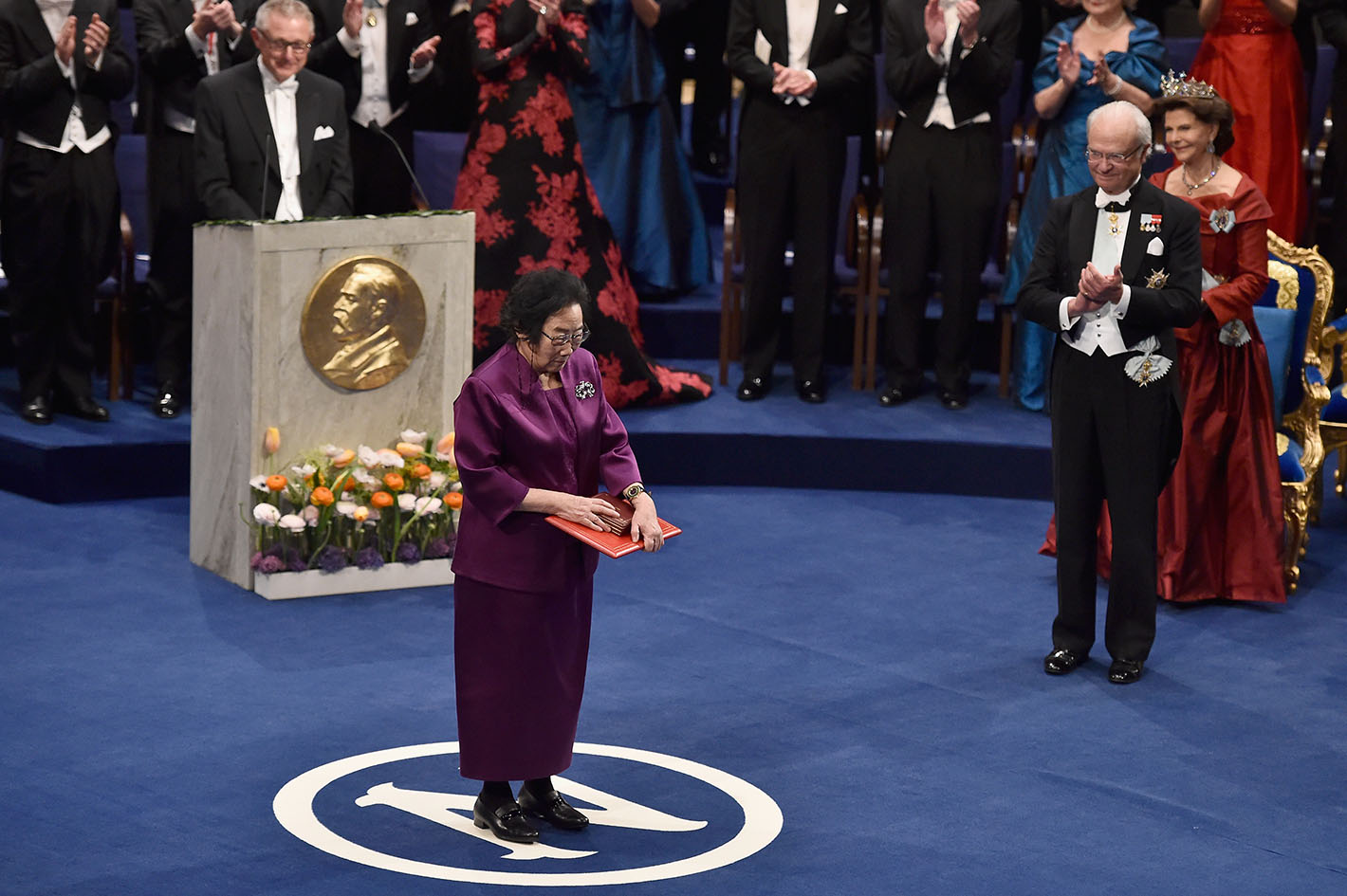 Η επικεφαλής καθηγήτρια Tu Youyou, βραβευμένη με Νόμπελ Φυσιολογίας /Ιατρικής, υποκλίνεται στο κοινό με το βραβείο Νόμπελ στα χέρια της μετά την απονομή του από τον βασιλιά Carl XVI Gustaf της Σουηδίας στο Μέγαρο Μουσικής στις 10 Δεκεμβρίου 2015 στη Στοκχόλμη της Σουηδίας.