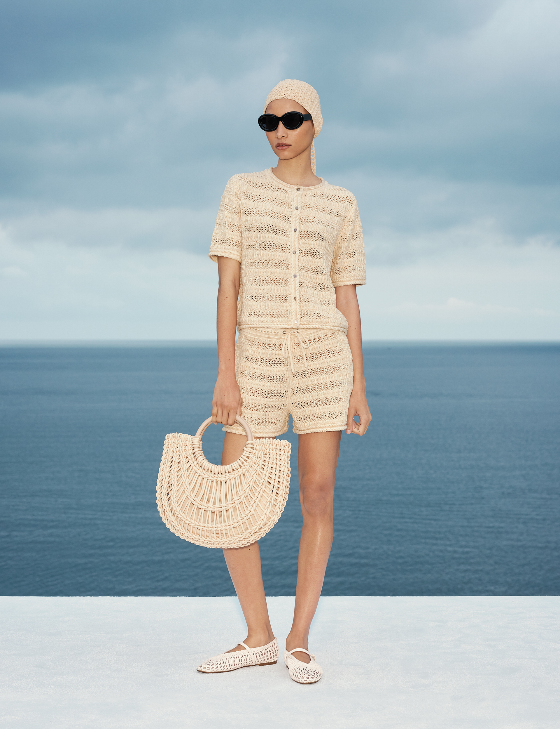 Γυναίκα φορώντας πλεκτό crochet σετ M&S σε παραθαλάσσιο τοπίο.